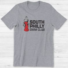 South Philly Swim Club Unisex Short Sleeve T-Shirt | Philly T-Shirt If you had a wrench, you were guaranteed hours of fun splashing around under the fire hydrant on a hot summer day. Everyone needs the perfect t-shirt to complement an everyday, laid-back look. The ideal top for so many occasions, this lightweight cotton tee will keep you comfy and looking smart. This t-shirt has ribbed knit collars to bolster shaping. The shoulders have taping for better fit over time. Dual side seams hold the g South Philly, Swim Club, Game Day Shirts, Fire Hydrant, Unisex Shorts, Summer Day, Summer Shirts, Wrench, Hot Summer