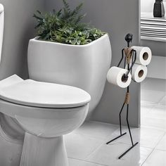 a white toilet sitting in a bathroom next to a planter with two rolls of toilet paper on it