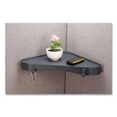 a corner shelf with a potted plant on it and a remote control attached to the wall