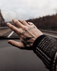 a person's hand on the dashboard of a car, with an arrow tattooed on it