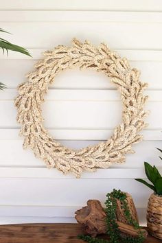 a rope wreath hanging on the wall next to some potted plants