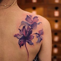 the back of a woman's shoulder with purple flowers on her left arm and chest