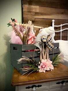 a wooden crate filled with fake flowers on top of a table next to a bed