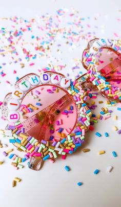 pink sunglasses with sprinkles and happy birthday written on the lenses are surrounded by confetti