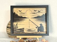 an image of a man fishing on the lake with birds flying over him and trees in the background