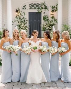 a group of women standing next to each other in front of a building with white flowers