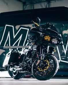 a black motorcycle parked in front of a wall with graffiti on it's side