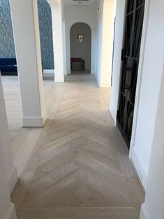 an empty hallway with white walls and wood flooring on either side of the door