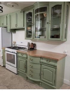 a kitchen with green cabinets and white appliances