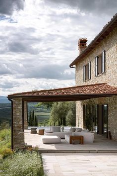 an outdoor living area with couches and tables on the side of a stone building