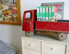 a red toy truck sitting on top of a white dresser next to a framed picture