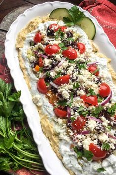 a platter filled with hummus, tomatoes and cucumber garnish