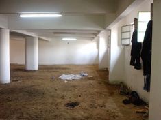 an empty room with clothes hanging on the wall and other items strewn about in it