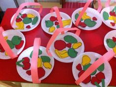 paper plates with fruit on them are sitting on a red table cloth covered in pink ribbon