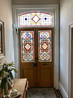 an entryway with stained glass windows and a wooden table in front of the door