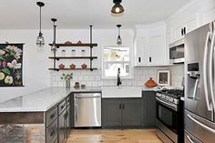 a kitchen with stainless steel appliances and white walls, wood flooring and open shelving