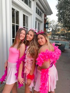 three girls dressed in pink and white posing for the camera