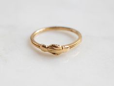 a gold ring that has two hands on it, and is sitting on a white surface