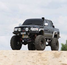 a large black truck on top of a dirt hill