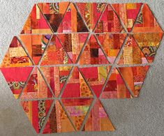 a piece of art made out of patchwork and scraps on the floor, including an orange hexagonal pattern