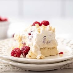 a piece of cake on a plate with raspberries and whipped cream frosting