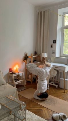 a woman doing yoga in her living room with candles on the floor and furniture around