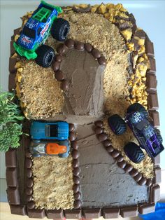 a birthday cake made to look like a monster truck track with cars on the side