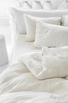 a bed with white linens and pillows on it