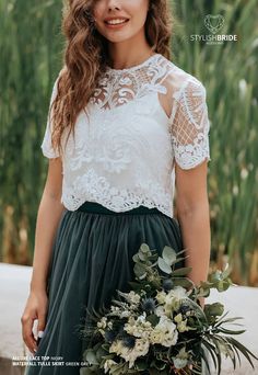 a woman wearing a white top and green skirt holding a flower bouquet in her hand