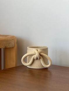 a white ceramic vase sitting on top of a wooden table next to a wood chair