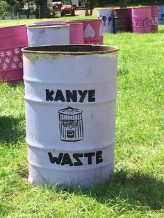 several buckets sitting in the grass with words on them that say kanye waste