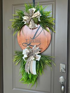 the front door is decorated with green and white wreaths, bow ties, and monogrammed leaves