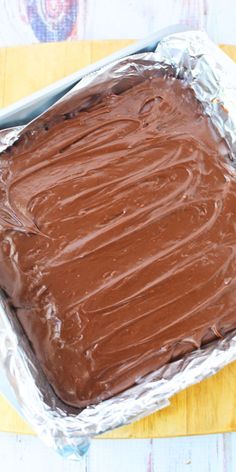 a chocolate cake sitting on top of a pan covered in tin foil and frosting