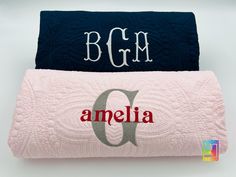 two monogrammed blankets with the letter q and an o on them, one in blue and one in pink