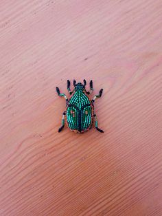 a green bug sitting on top of a wooden table