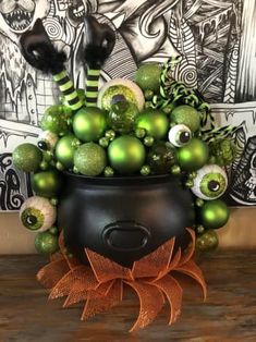 a pot filled with lots of green ornaments on top of a wooden table next to a wall