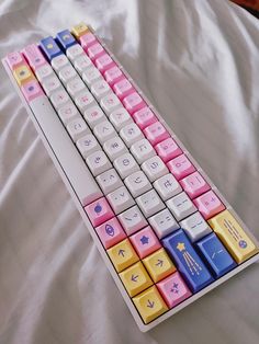 a multicolored keyboard sitting on top of a white bed covered in sheets and pillows