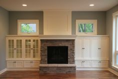 an empty living room with built in cabinets and a fireplace