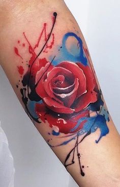 a red rose tattoo on the arm with blue splatters and watercolors