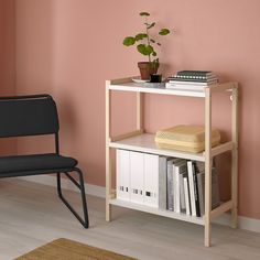 a chair sitting next to a book shelf with books on it and a potted plant