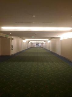 an empty hallway with green carpet and lights