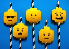 four yellow candles with black and white striped straws in the shape of lego faces