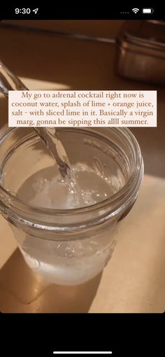 a glass jar filled with water sitting on top of a table next to a spoon