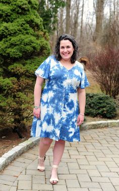 a woman in a blue and white dress standing on a brick walkway