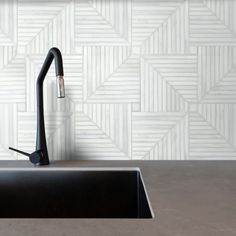 a black kitchen sink sitting under a faucet next to a white tiled wall