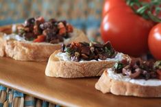 three pieces of bread with various toppings on them sitting on a table next to tomatoes