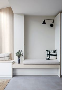 a white room with a bench, plant and lamp