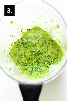 a blender filled with green liquid on top of a white table