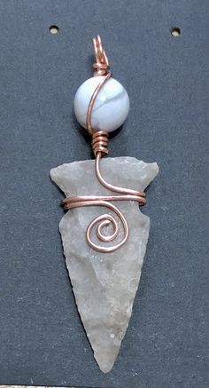 a piece of wire wrapped around a rock with a white bead on it's end