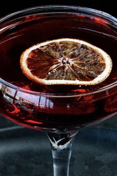 a close up of a drink in a glass with an orange slice on the rim